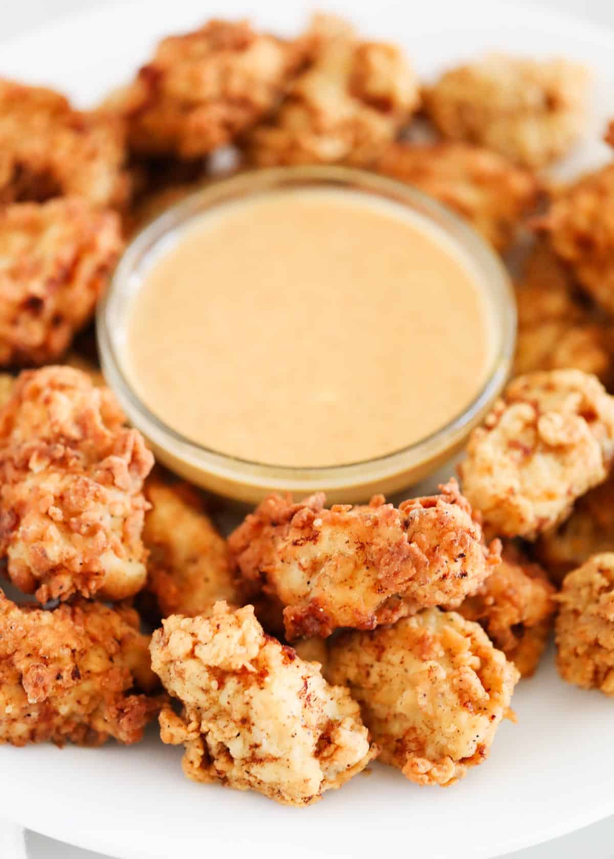 Chick fil a nuggets on white plate with sauce.