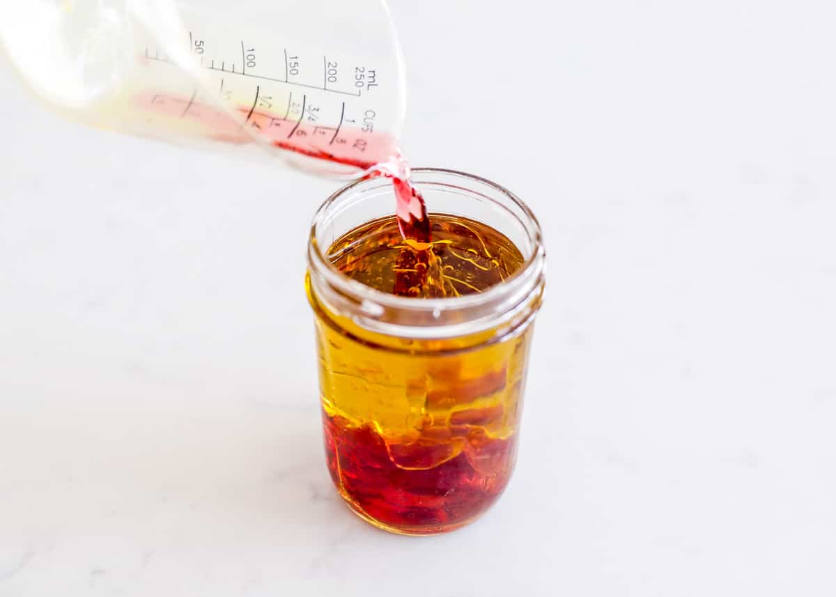 Pouring vinegar into jar of italian dressing.