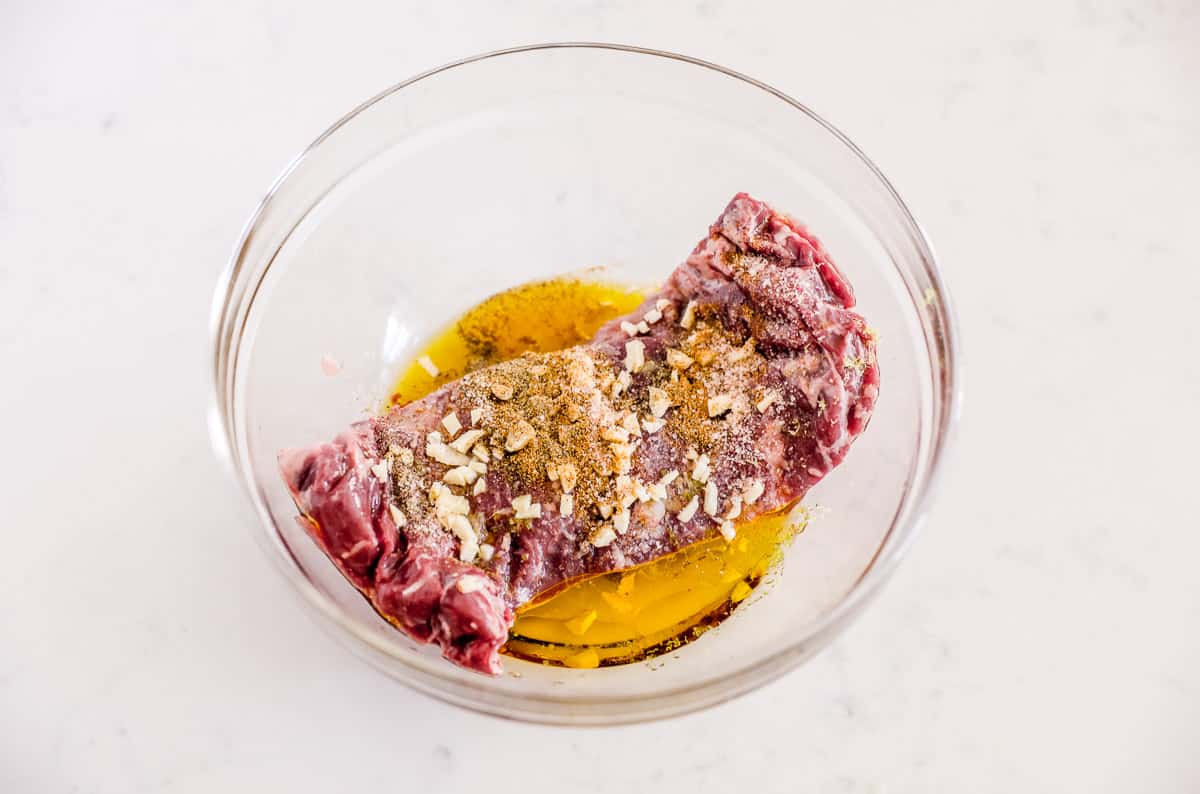 Skirt steak marinating in bowl.