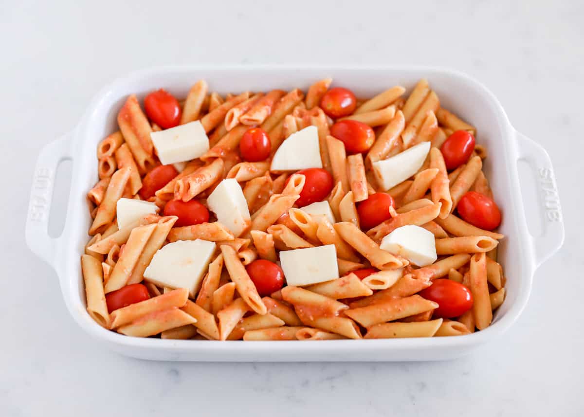 Noodles, tomatoes and cheese in baking dish.