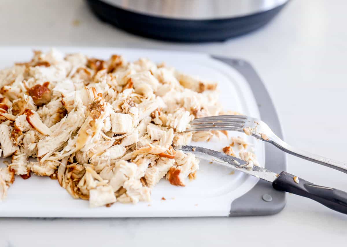 Shredding chicken on cutting board.