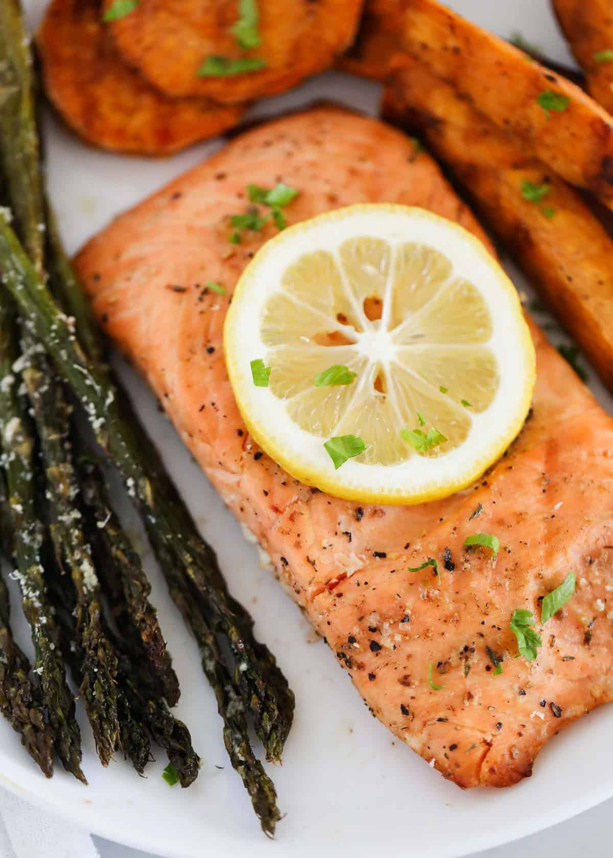 Salmon, asparagus, and sweet potatoes on white plate.