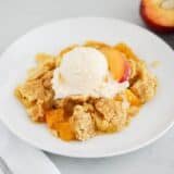 peach dump cake and ice cream on white plate