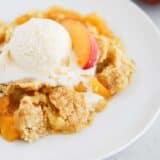 peach dump cake and ice cream on white plate