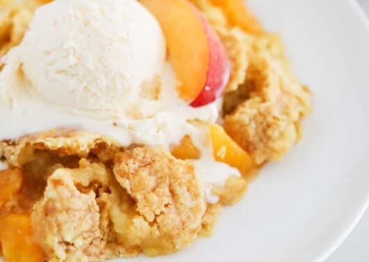 peach dump cake and ice cream on white plate