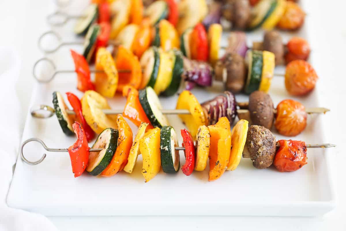 Vegetable skewers on white platter.