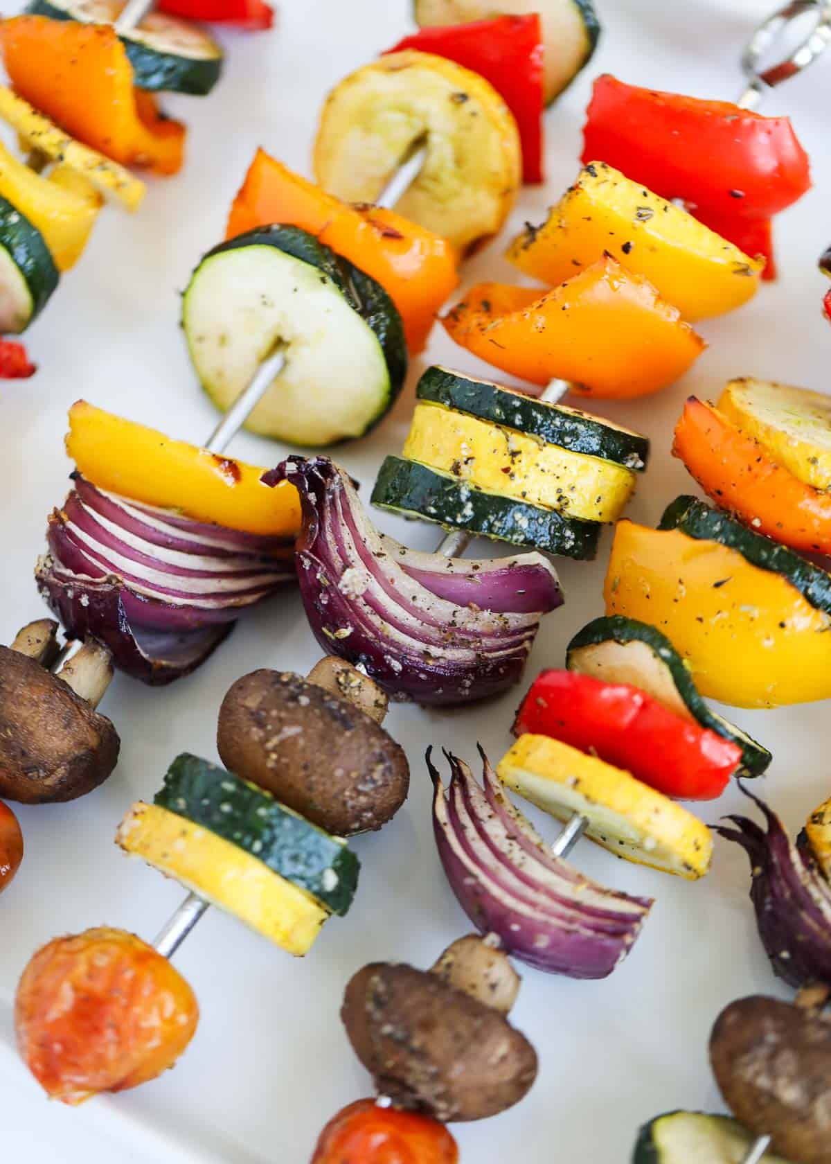 Vegetable skewers on white platter.