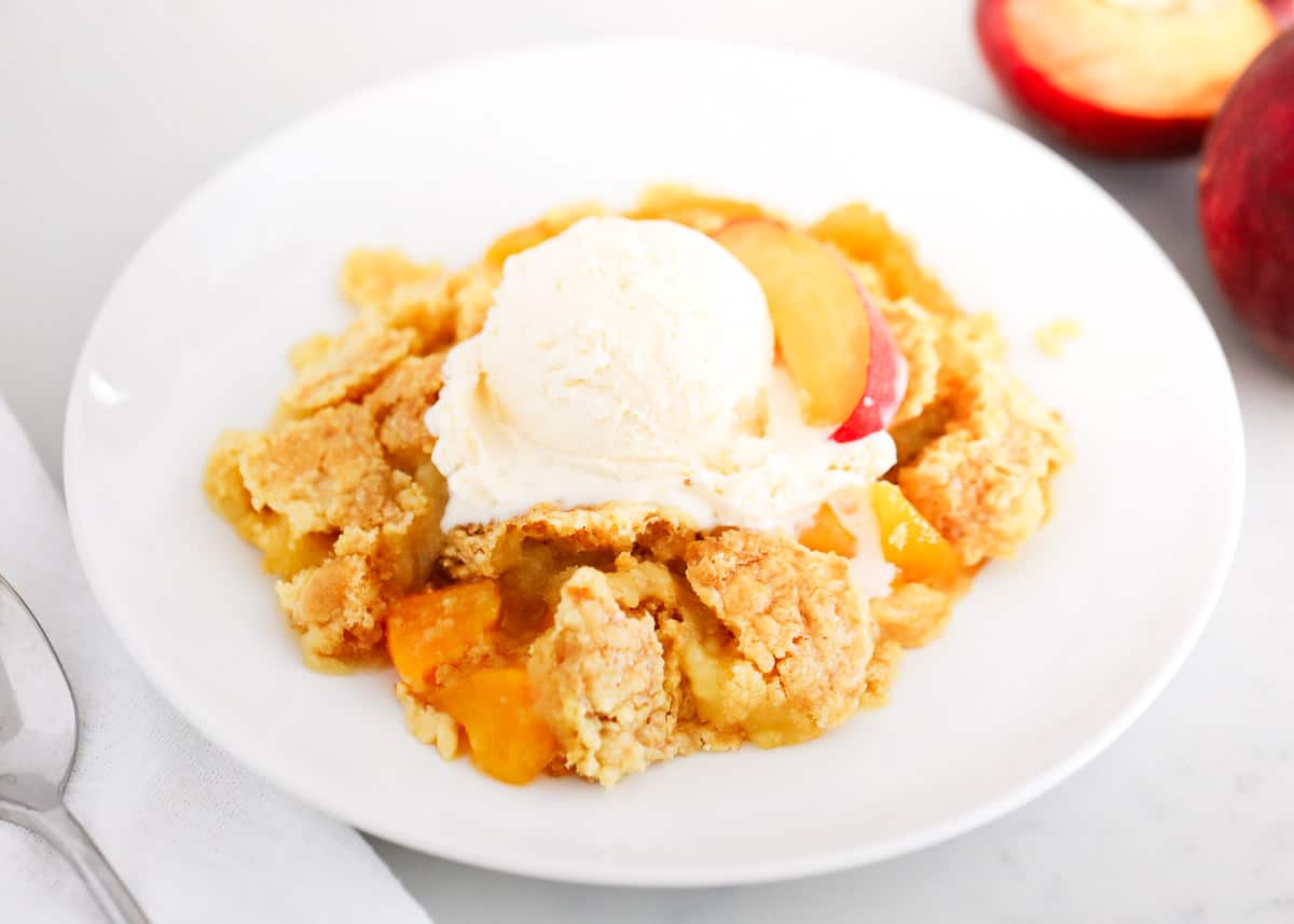 Peach dump cake with ice cream in a bowl.