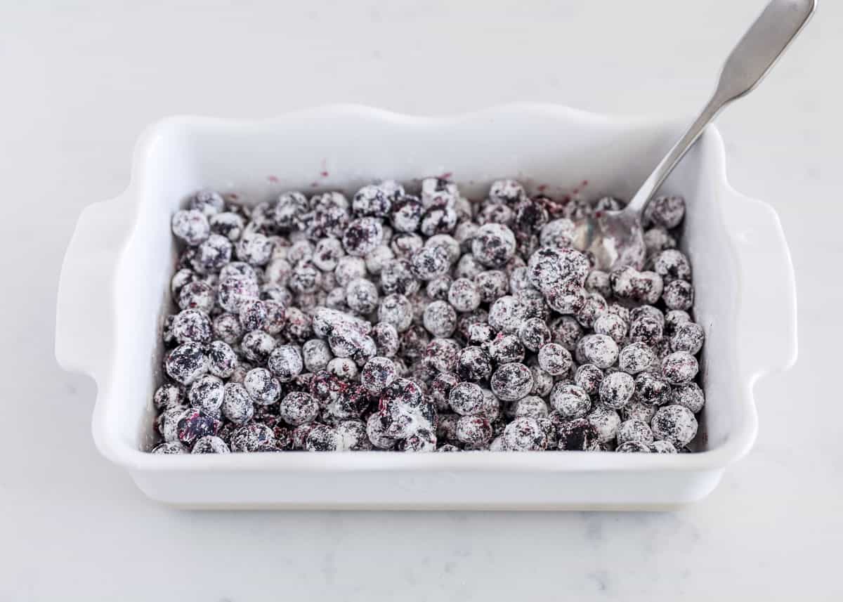 Blueberries tossed in flour in white baking dish.