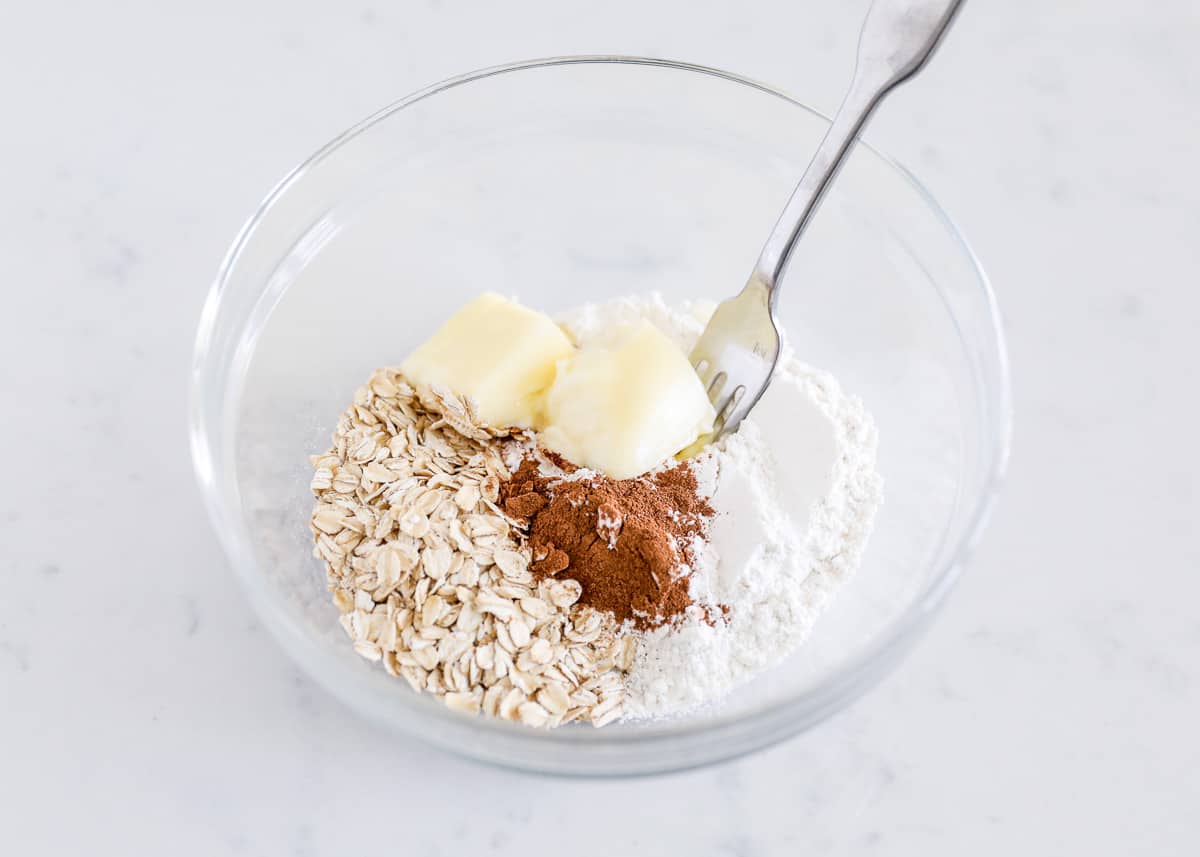 Butter, oats, cinnamon and flour in a bowl.