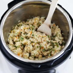 Instant Pot chicken and rice garnished with parsley and being served with a wood spoon.