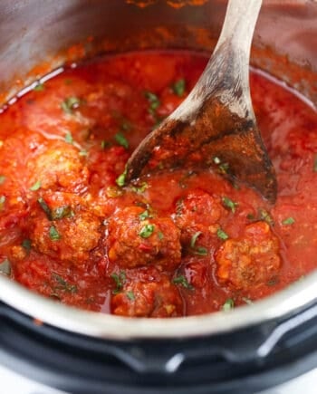 Instant Pot meatballs and marinara sauce in the pressure cooker with a serving spoon.