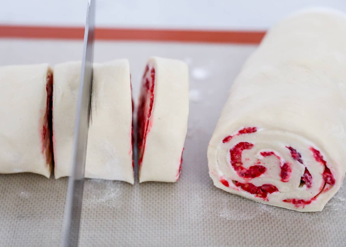 slicing raspberry rolls with knife