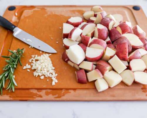 sliced potatoes and rosemary on cutting board