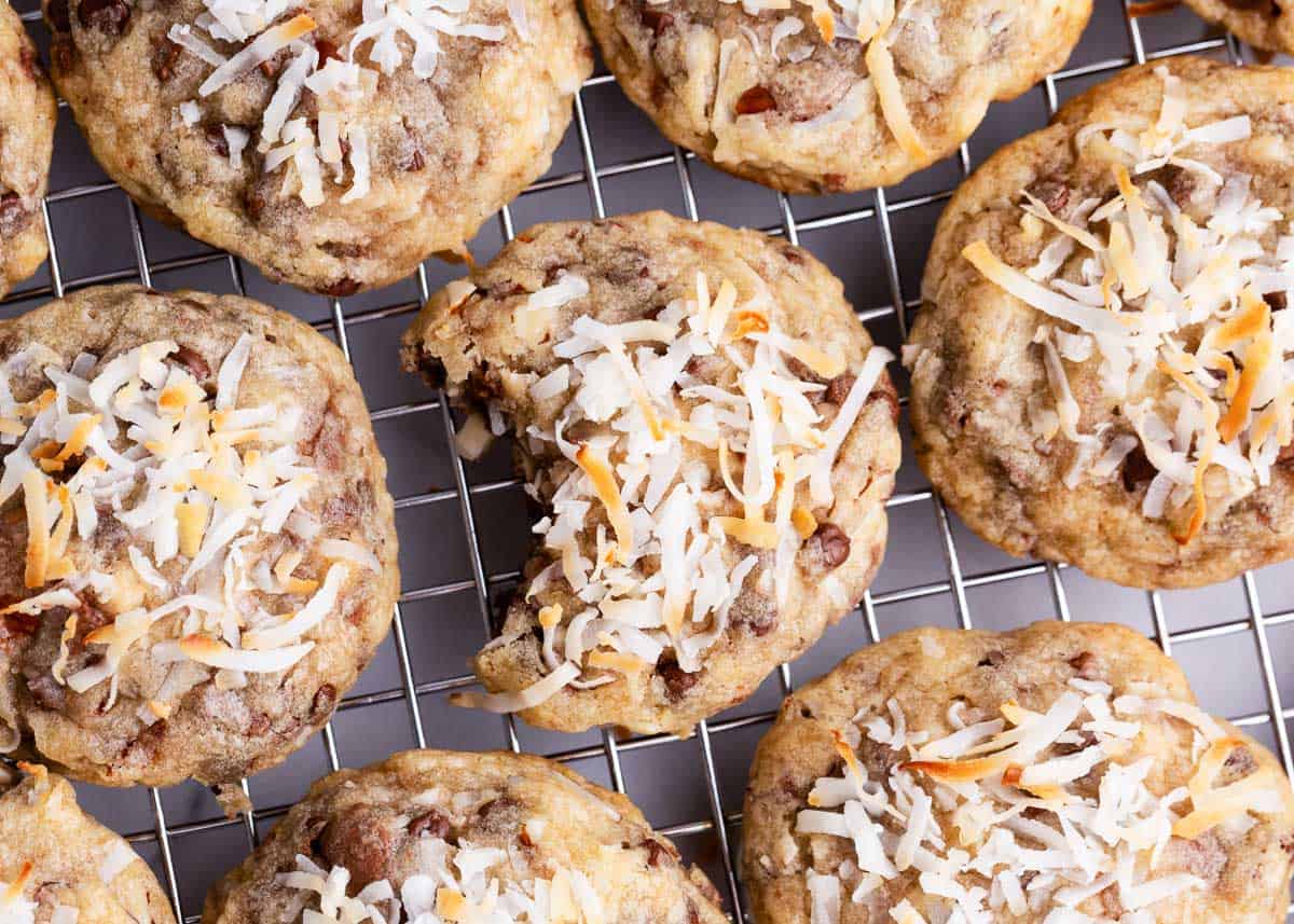 Rich and buttery cookie dough packed full of shredded coconut, chocolate chips, almonds and Almond Joy candy pieces. These Almond Joy cookies are an over-the-top indulgent treat that will become a new favorite! Almond joy cookie on cooling rack.