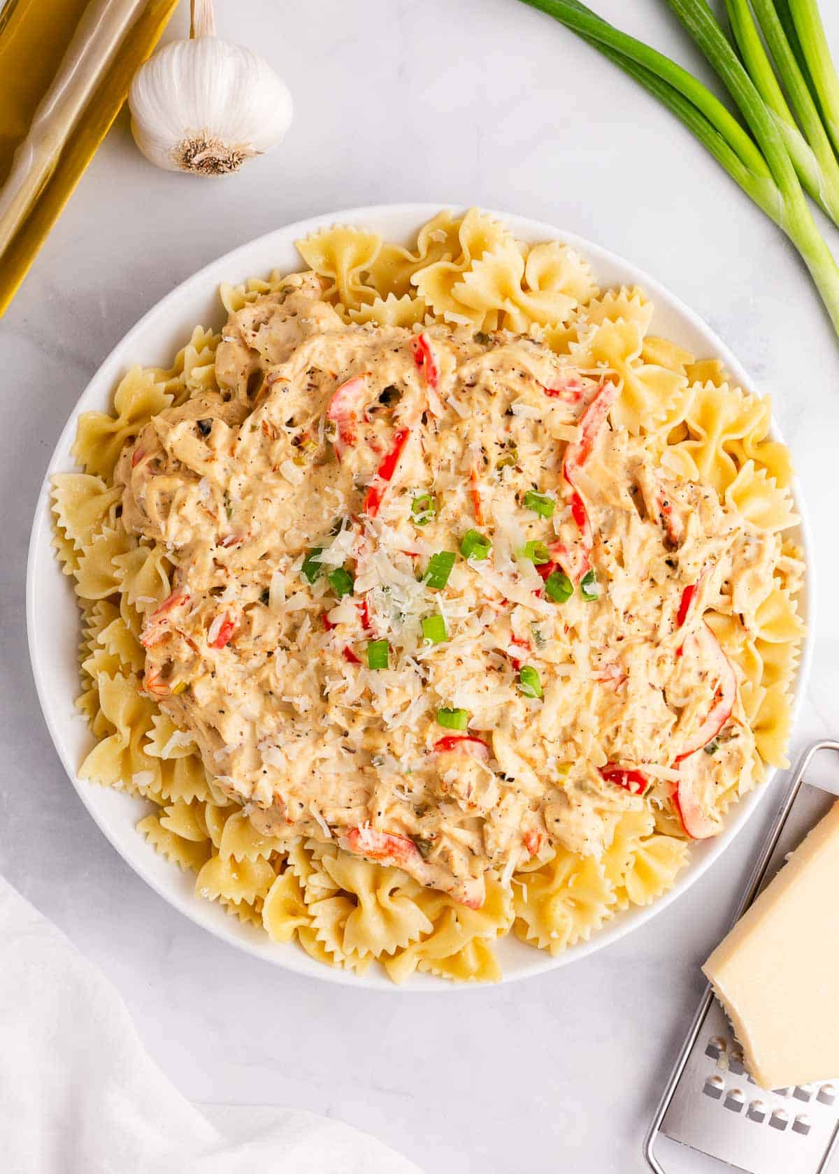 Big bowl of creamy chicken pasta on marble countertop. 