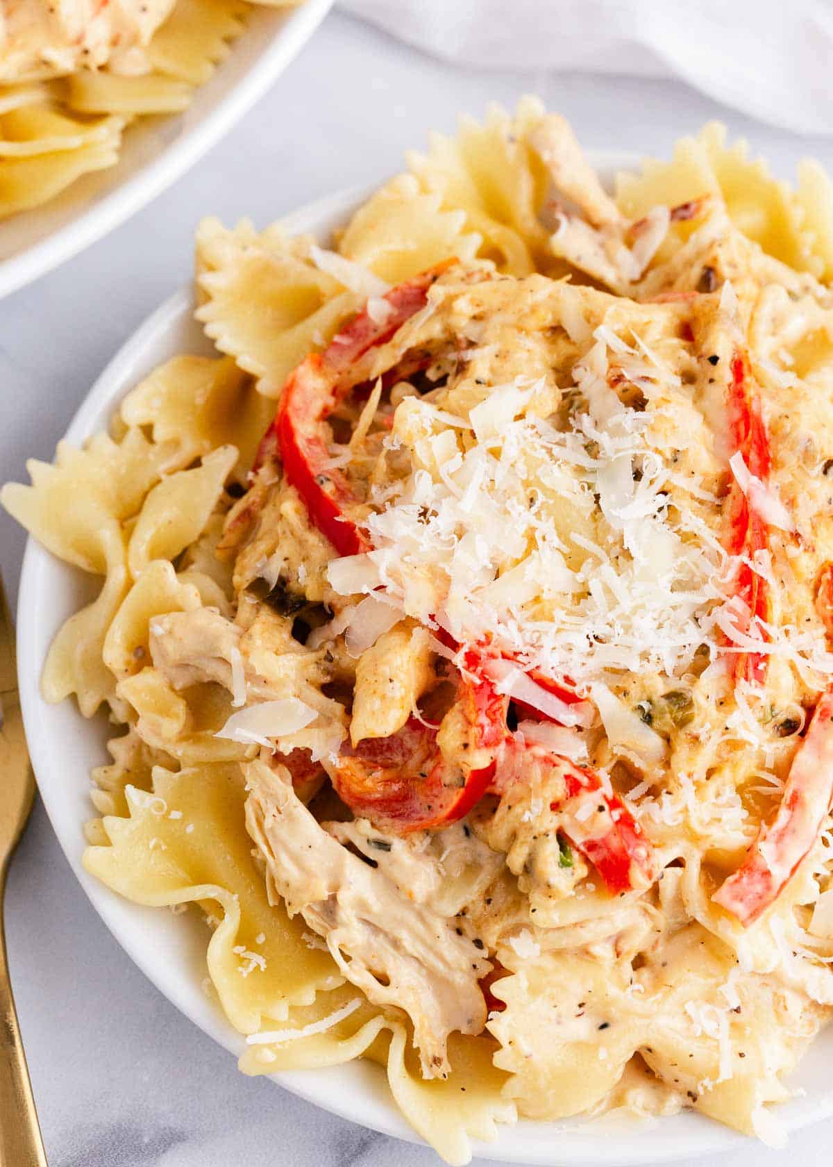Creamy chicken pasta with peppers on white plate.