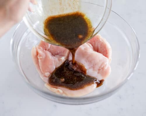 pouring marinade over chicken