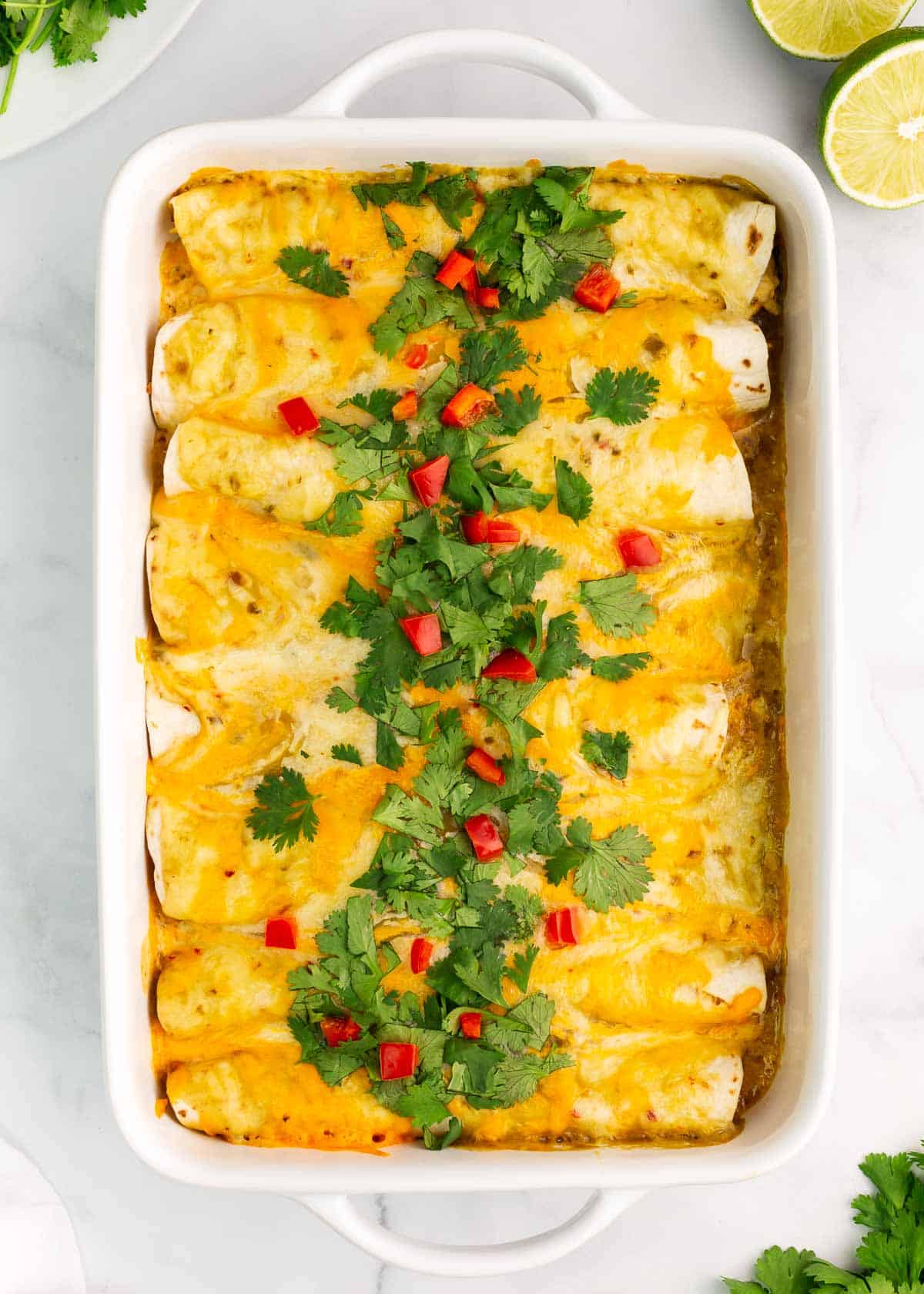 Green chile chicken enchiladas in casserole dish.