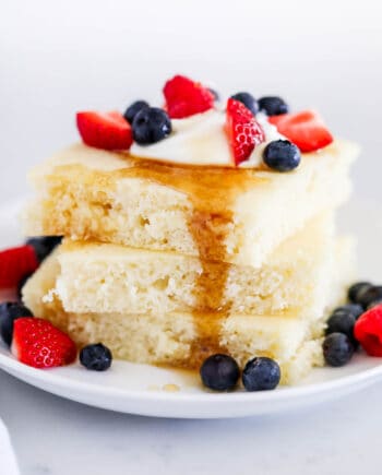 stack of sheet pan pancakes with syrup and berries