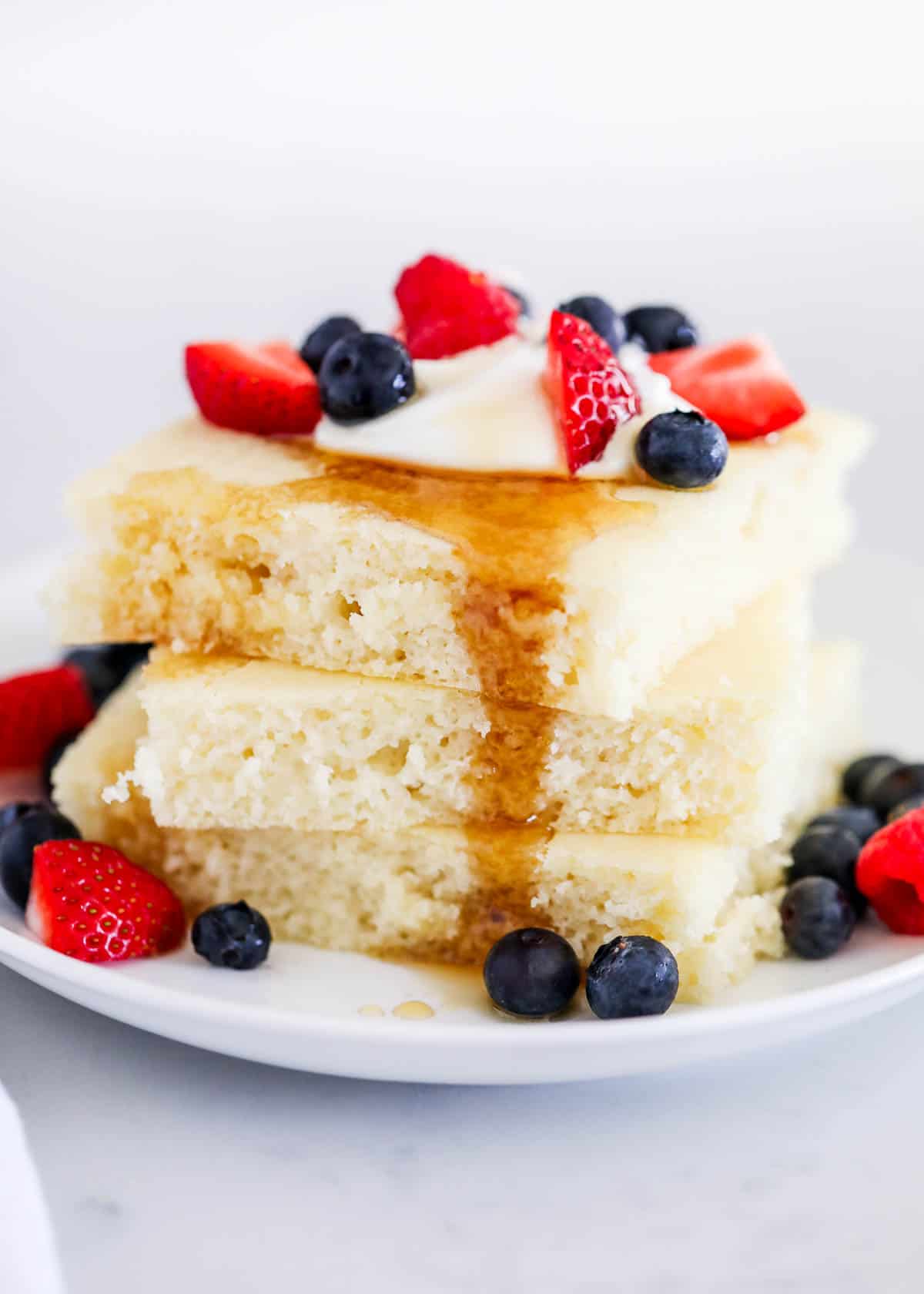 stack of sheet pan pancakes with syrup and berries