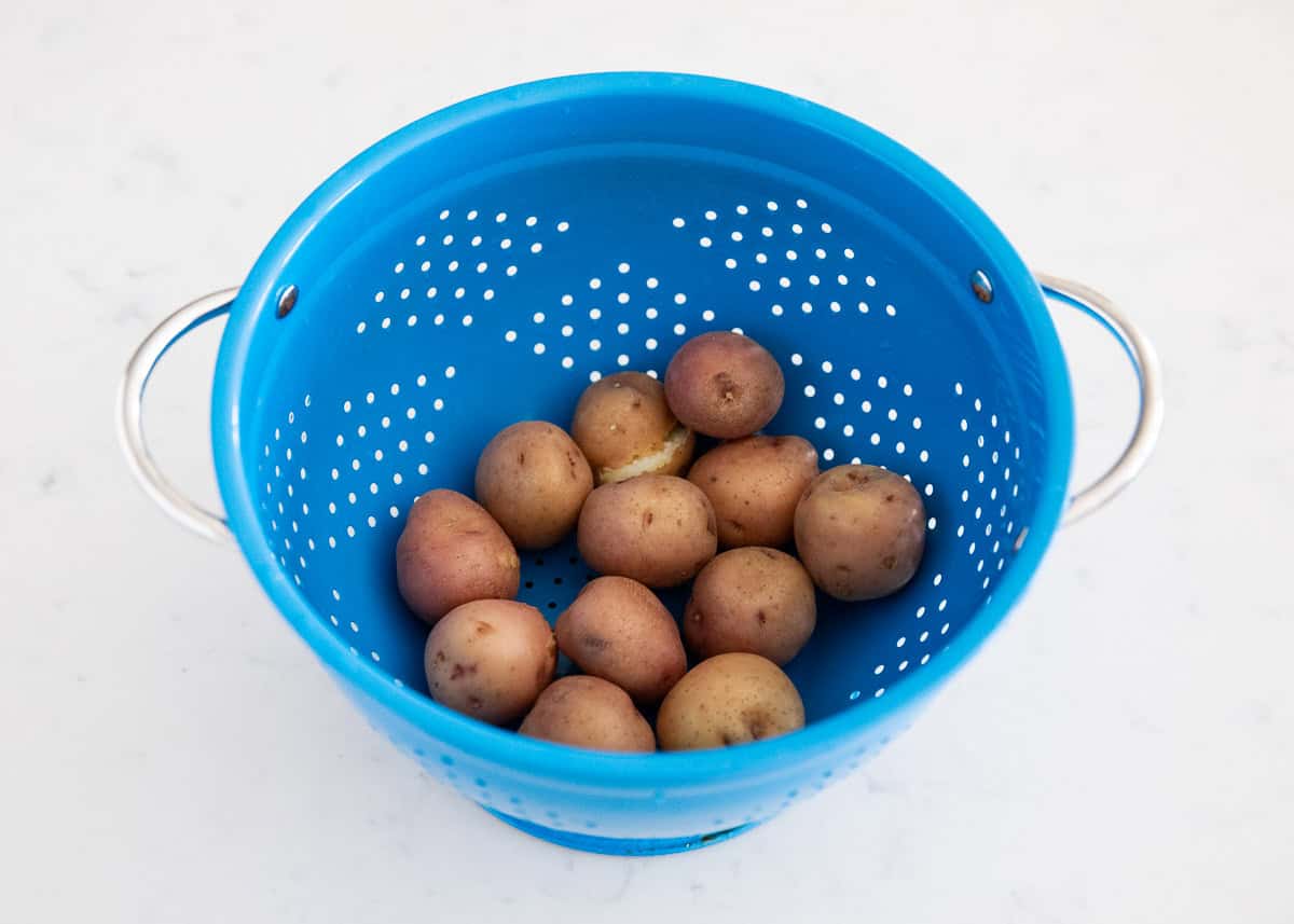 Potatoes draining in a blue colander.