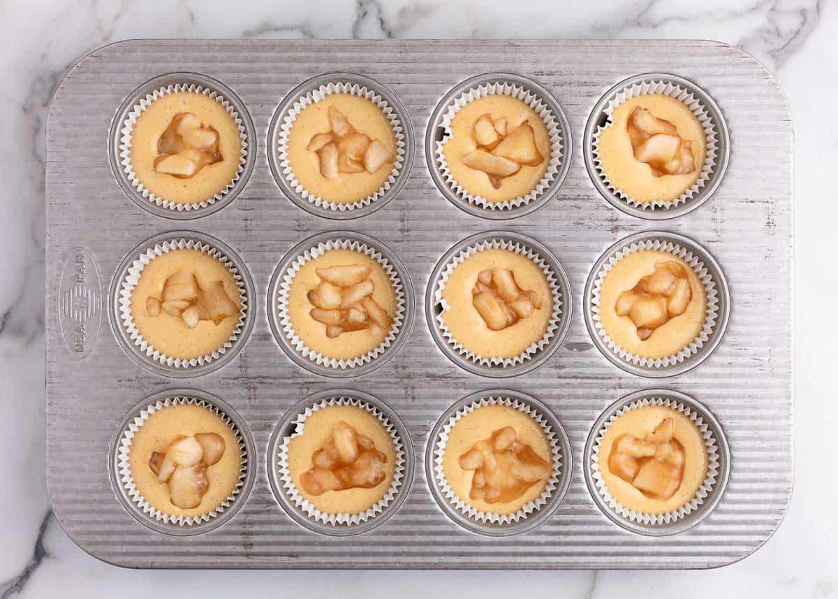 cupcake batter in muffin tin with apple filling