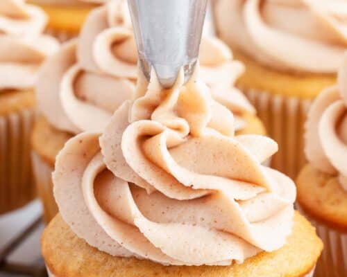 piping cinnamon frosting on apple pie cupcake