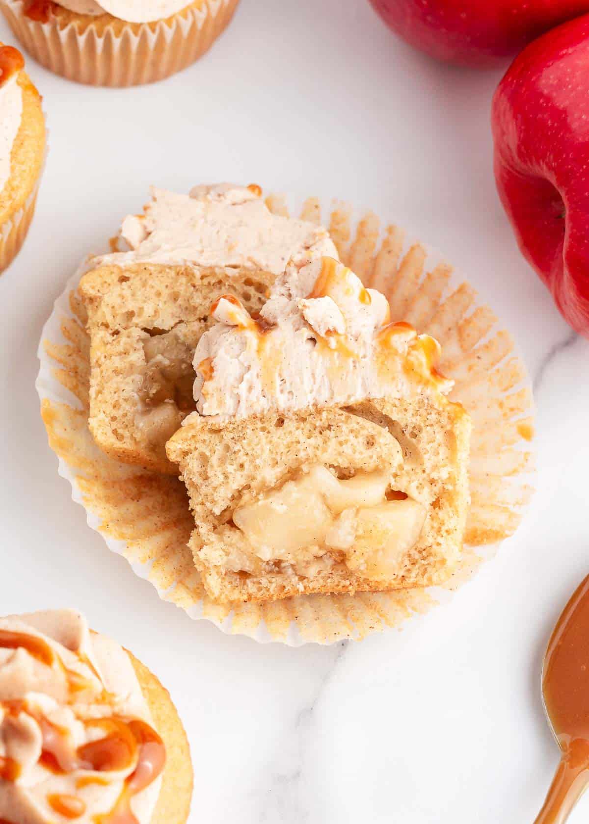 One apple pie cupcake cut in half to show apple filling stuffed inside.