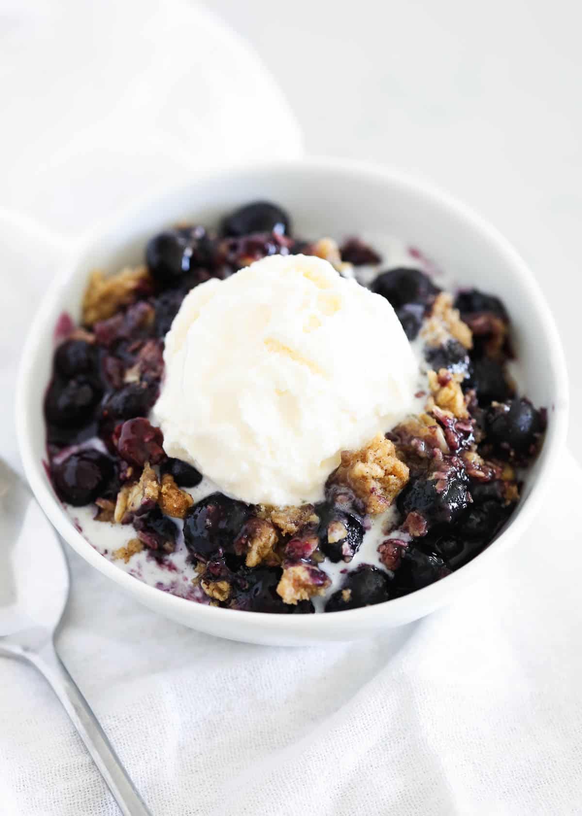 Blueberry crisp with ice cream in a bowl.