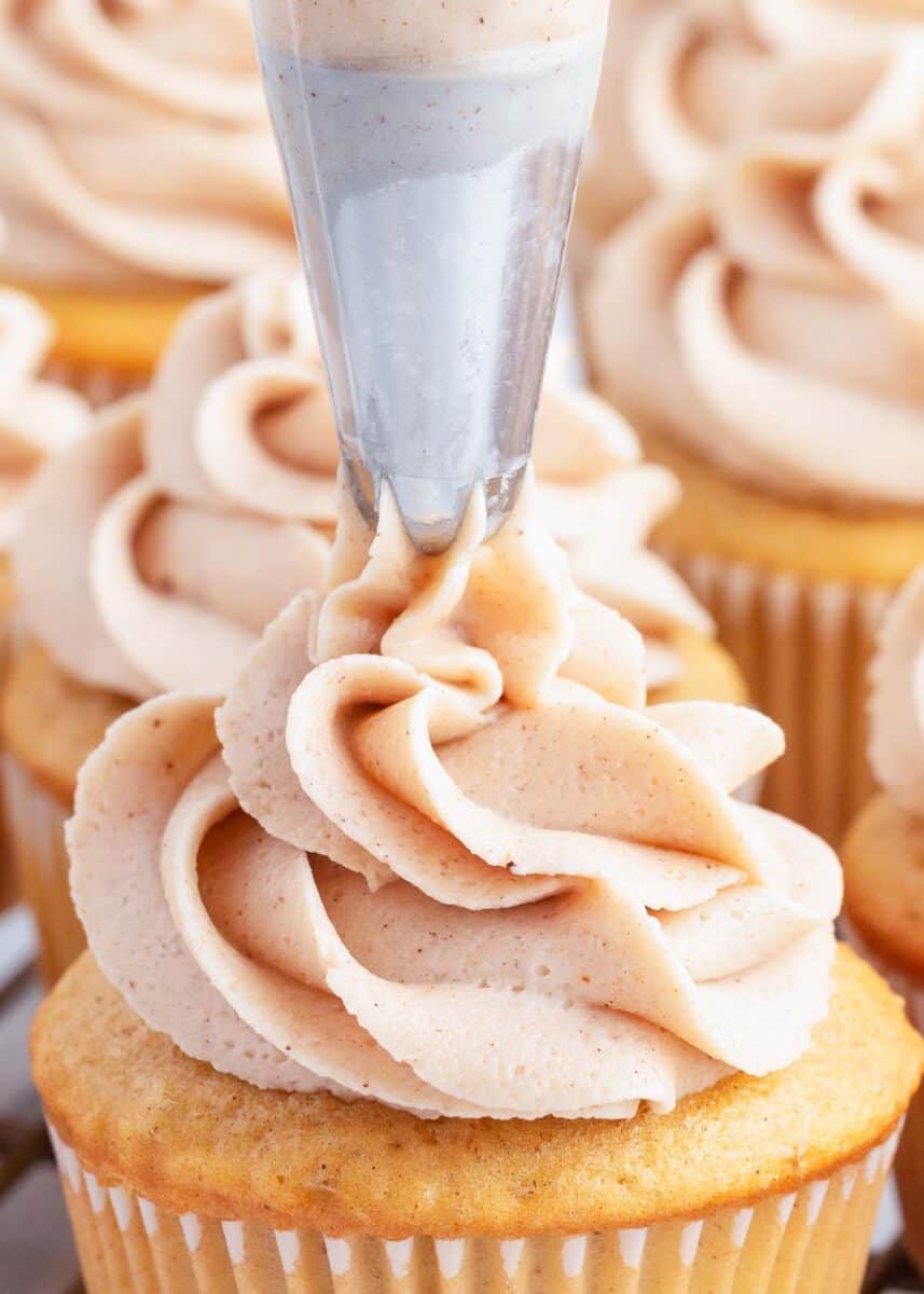 piping cinnamon buttercream on cupcake