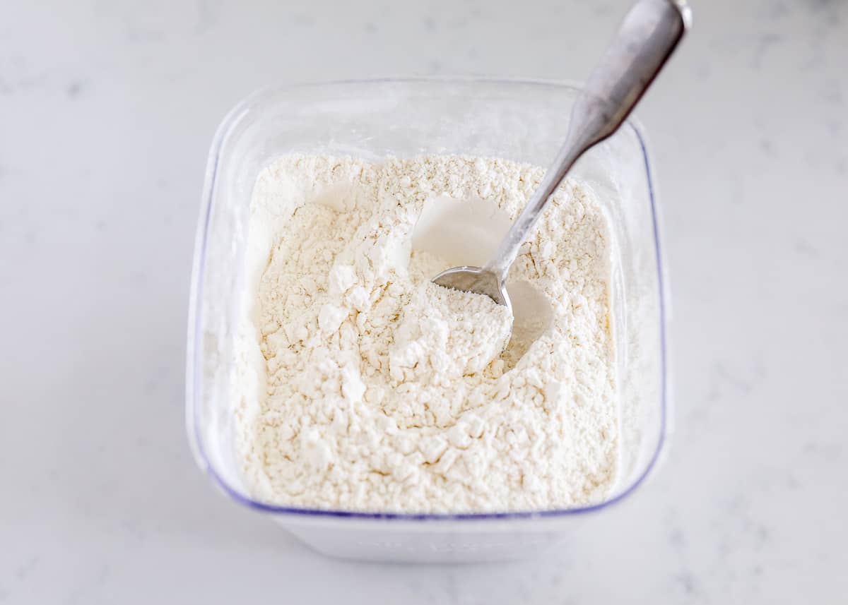 Learn how to measure flour the right way and avoid common baking mistakes! An easy-to-follow simple guide for bakers of all skill levels yielding amazing results every time! spoon in the flour container