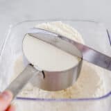 pressing the flour off the cup with the knife