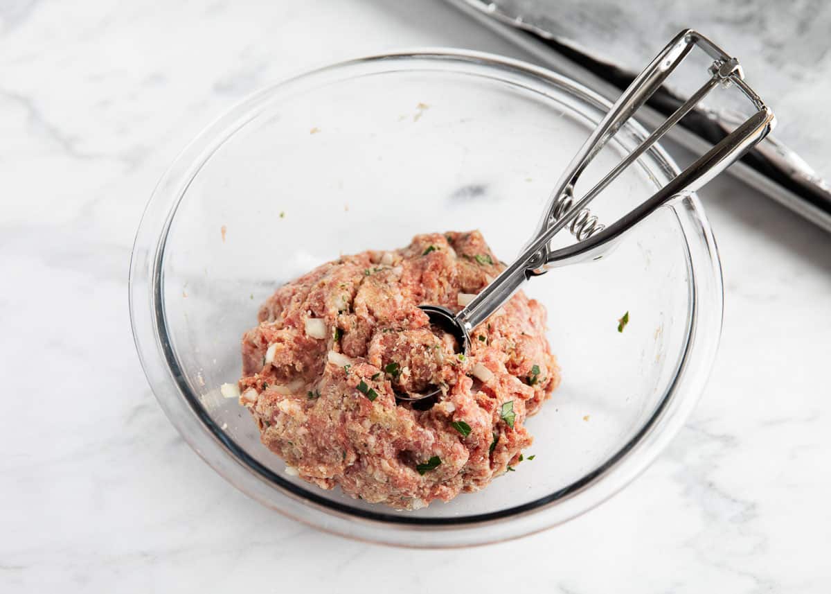 Instant pot meatball mixture in bowl with a cookie scoop to make round meatballs.