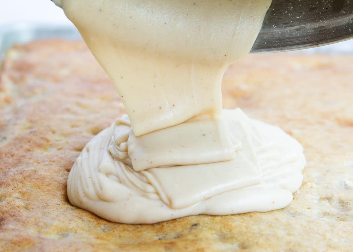 pouring brown butter frosting on cake