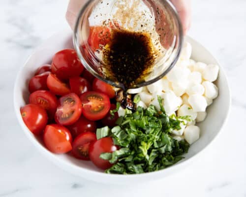 pouring dressing over caprese salad
