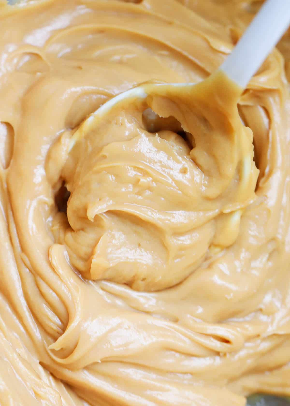 Caramel cream cheese frosting with a white spatula.