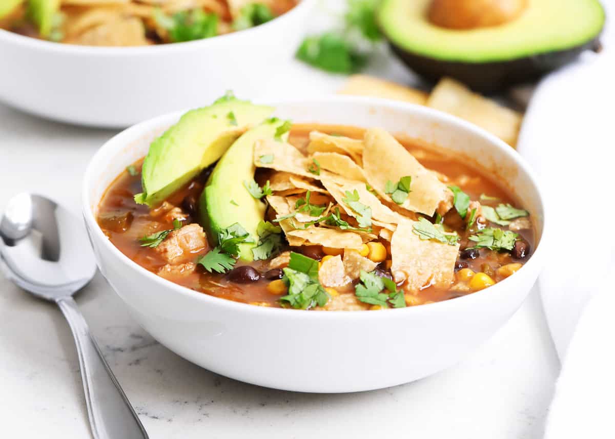 This chicken tortilla soup recipe is made in ONE pot in 30 minutes. Always a crowd pleaser and tastes great loaded with cheese, avocado and tortilla chips. chicken tortilla soup in bowl