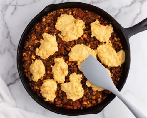 chili skillet with spoonfuls of cornbread on counter