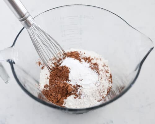 whisking flour and cocoa powder in glass bowl