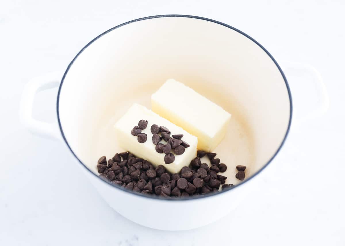 Butter and chocolate chips in white stovetop pan.