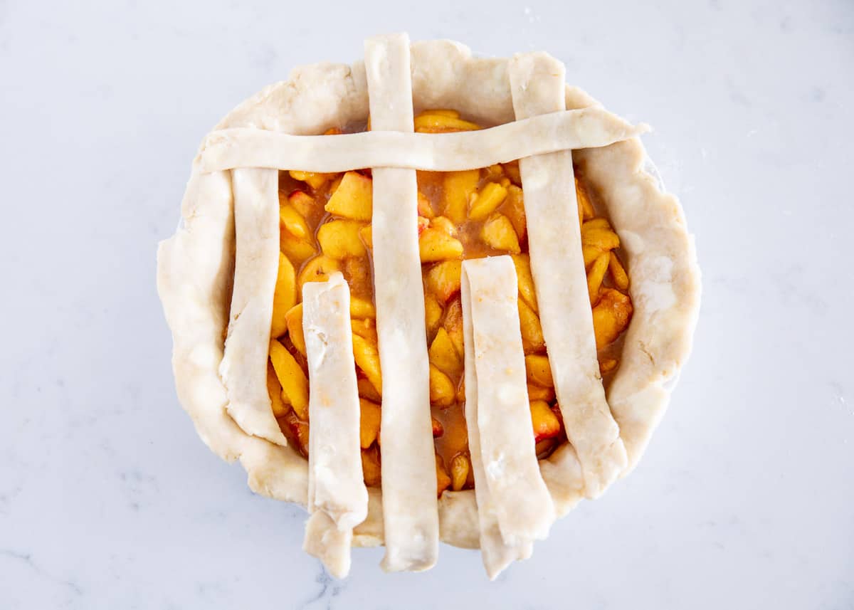 weaving pie crust on top of peach pie