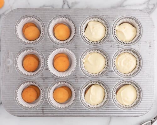 cheesecake filling on top of vanilla wafers in cupcake liners