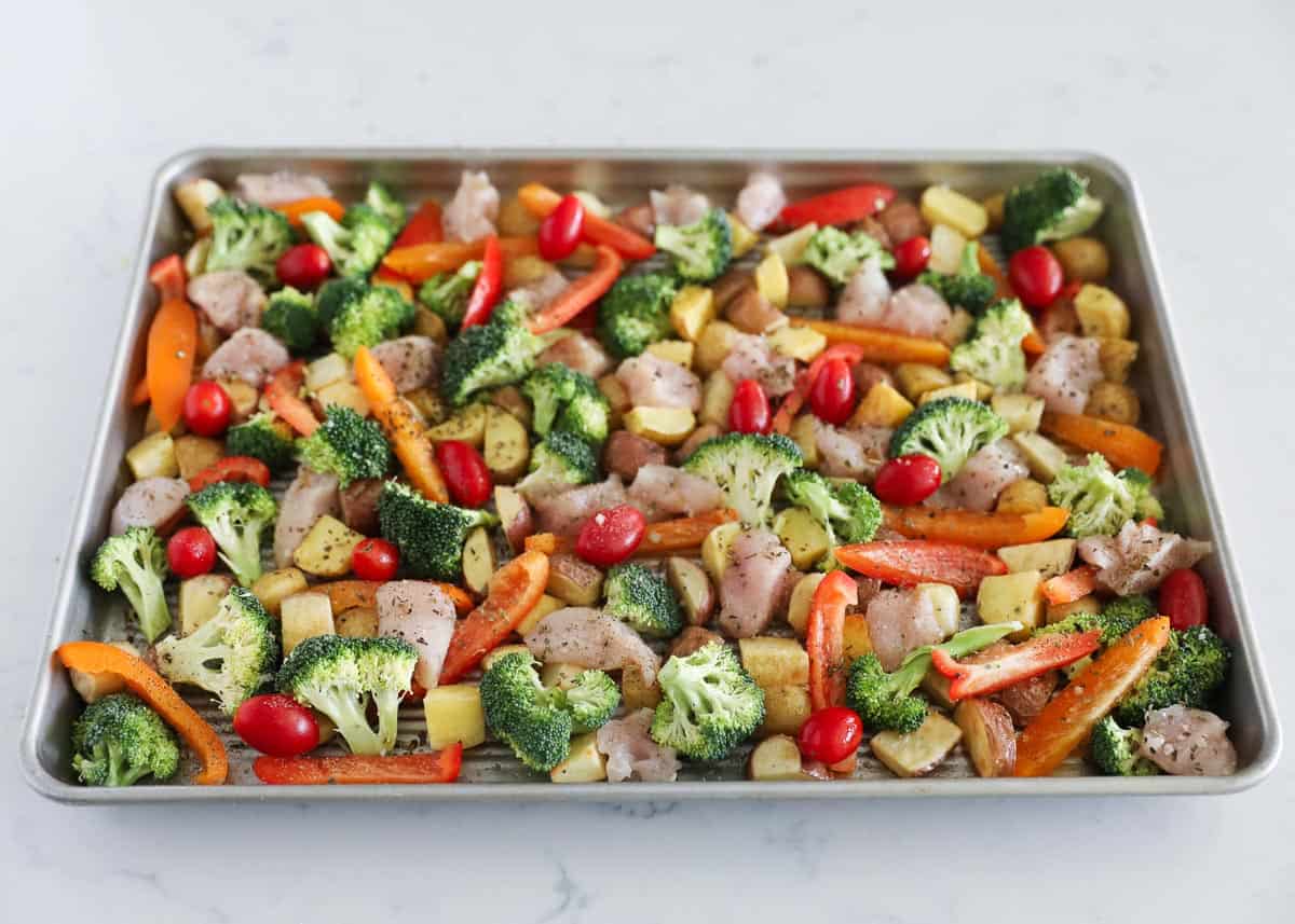 prepping chicken and vegetables on sheet pan