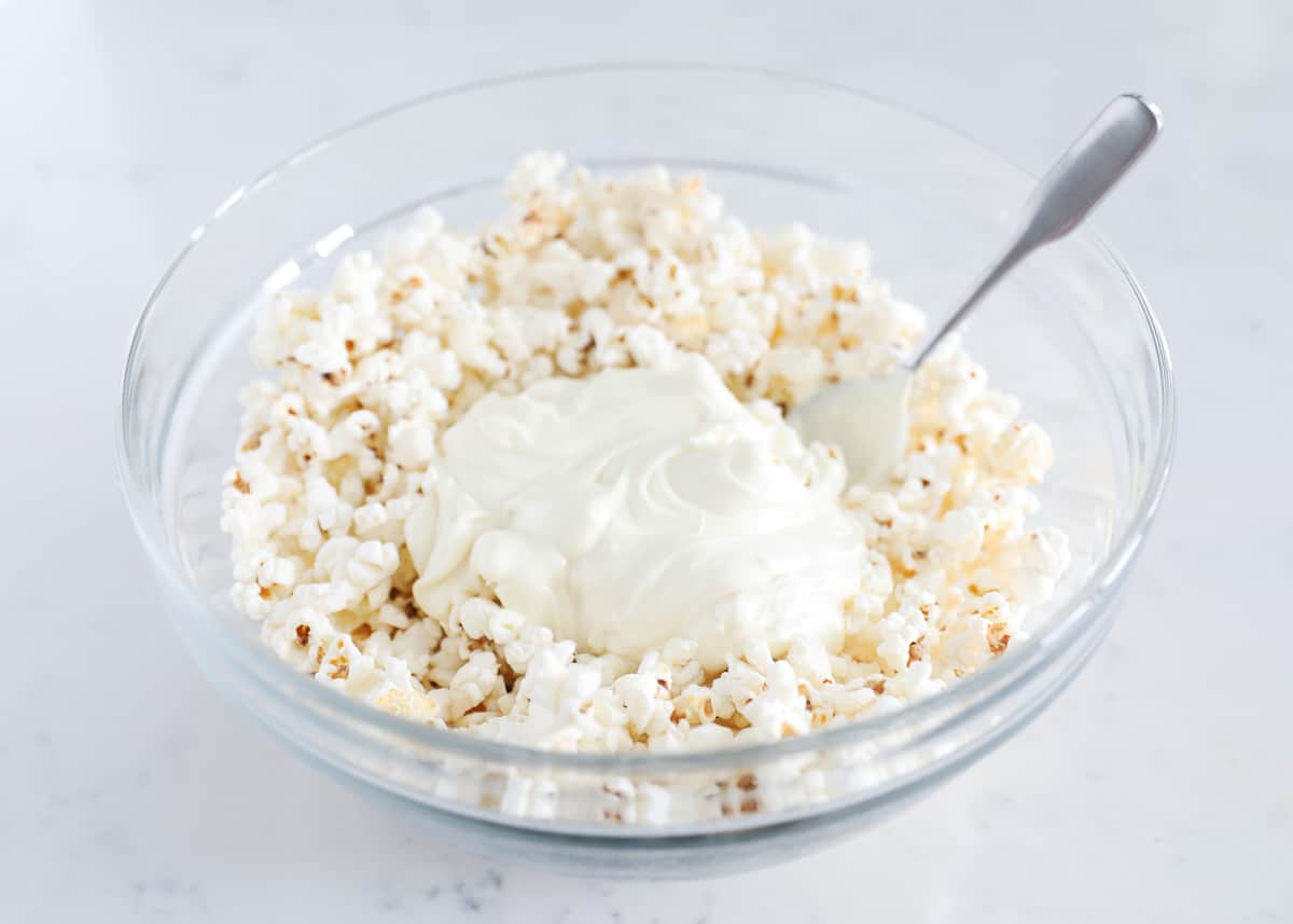 White chocolate and popcorn in glass bowl.