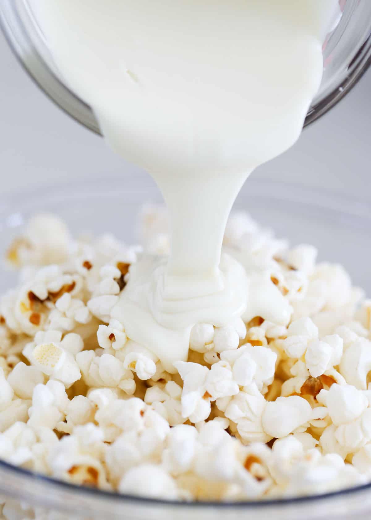 pouring white chocolate over popcorn