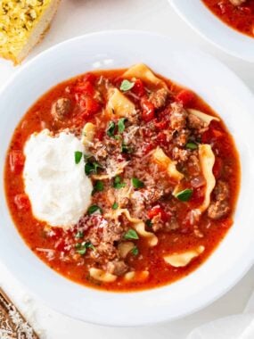 Hearty crockpot lasagna soup with sausage, lasagna noodles, tomatoes, and a dollop of ricotta cheese.