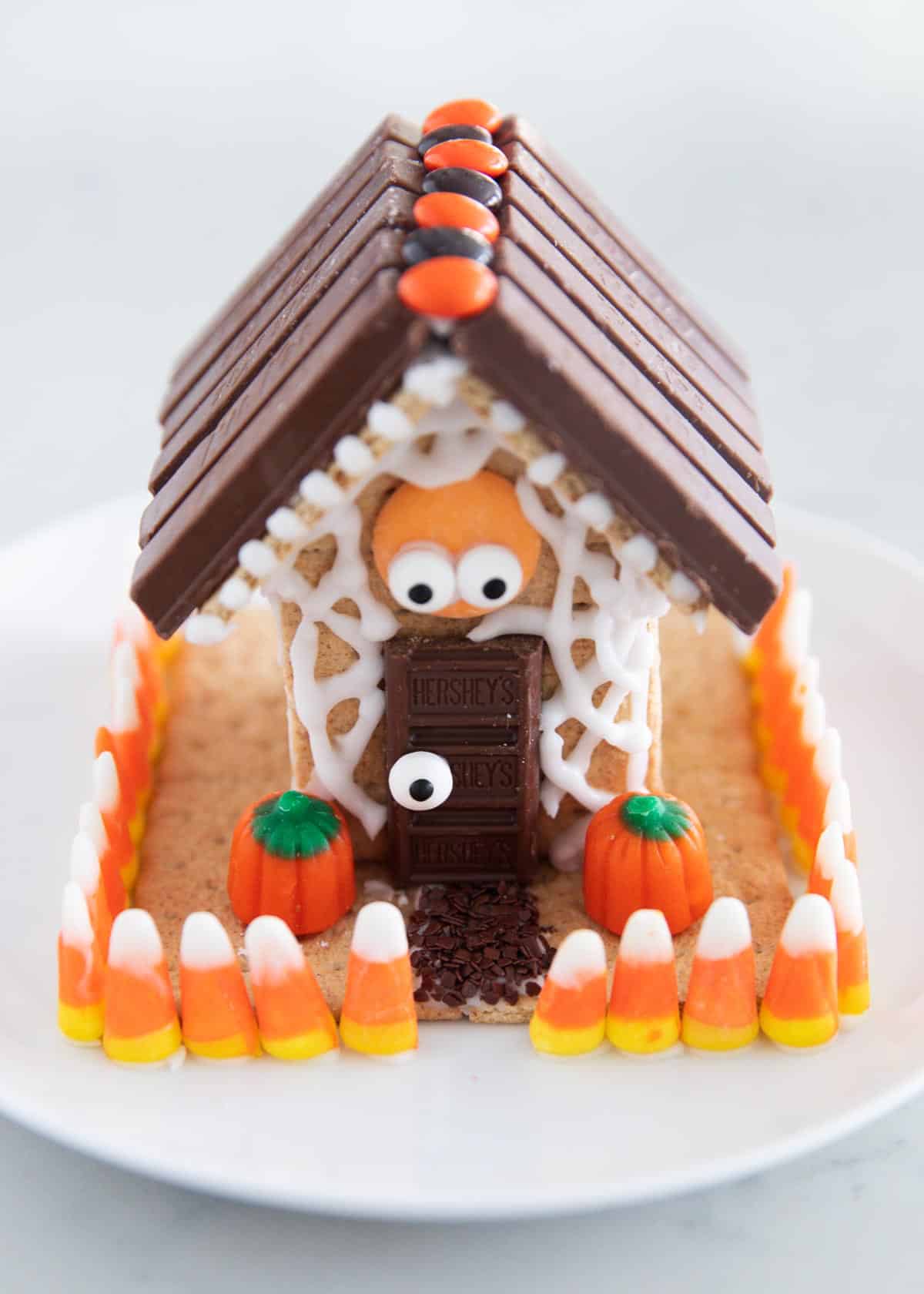 Spooky Halloween gingerbread house with candy decorations on a plate.