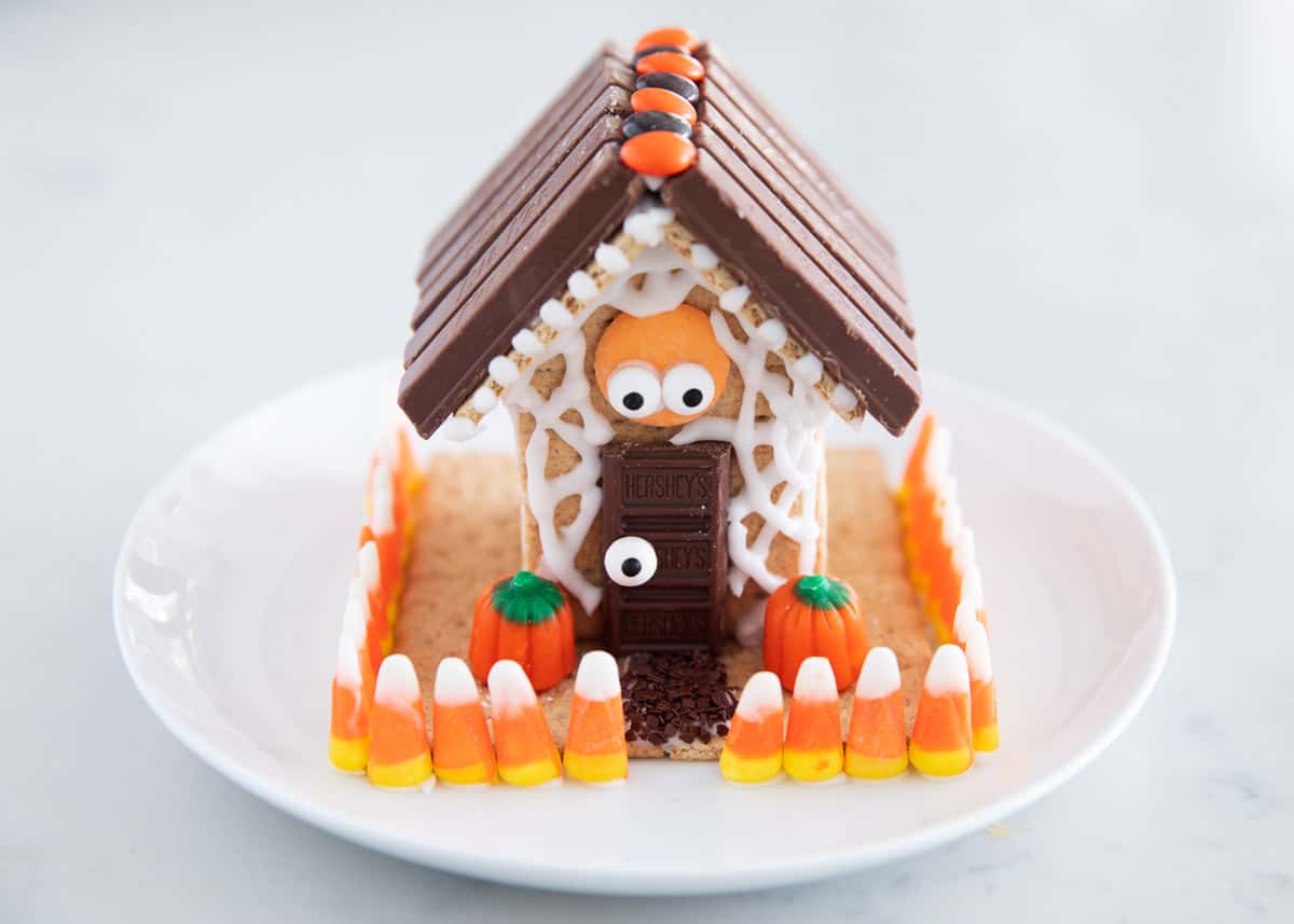 A haunted Halloween gingerbread house on a plate decorated with candy and icing.