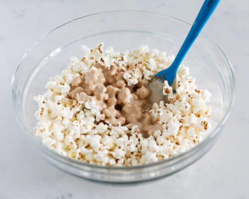 mixing popcorn and cookie butter in bowl